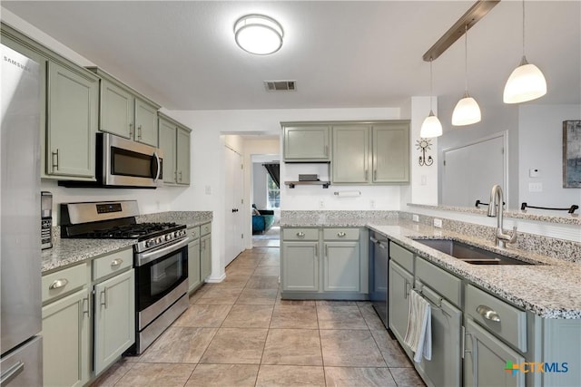 kitchen with green cabinets, visible vents, light stone counters, a sink, and stainless steel appliances
