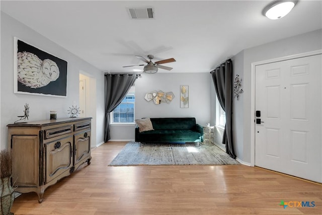 interior space featuring light wood-style floors, visible vents, baseboards, and a ceiling fan