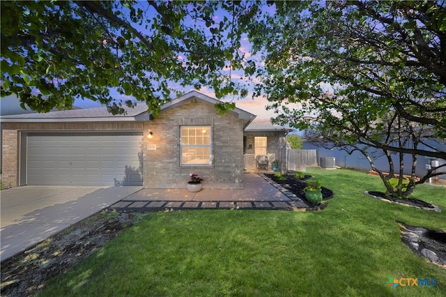 ranch-style home featuring a front yard, an attached garage, fence, concrete driveway, and brick siding