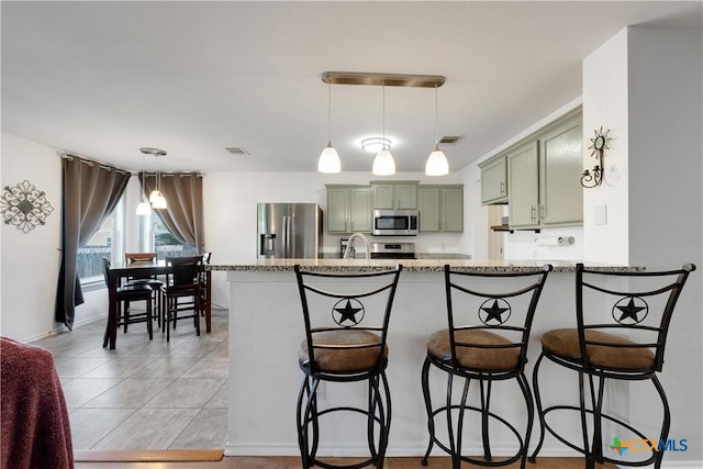 kitchen with visible vents, a breakfast bar area, appliances with stainless steel finishes, and green cabinetry