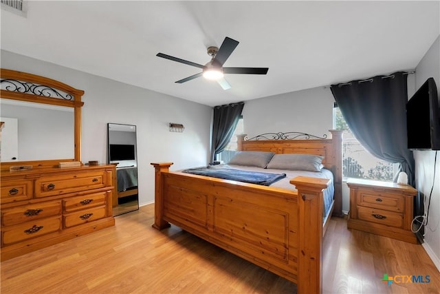 bedroom with light wood-style floors, a ceiling fan, and visible vents