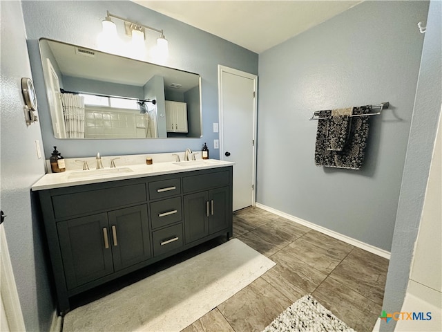 bathroom with a shower with shower curtain, double vanity, a sink, and baseboards
