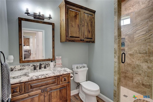 full bath featuring vanity, wood finished floors, baseboards, a stall shower, and toilet