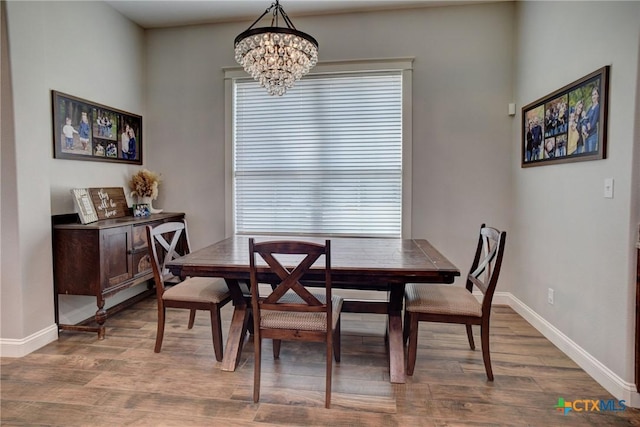 dining area featuring wood finished floors, baseboards, and a chandelier