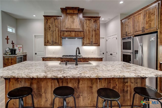 kitchen featuring a large island, decorative backsplash, appliances with stainless steel finishes, and light stone countertops