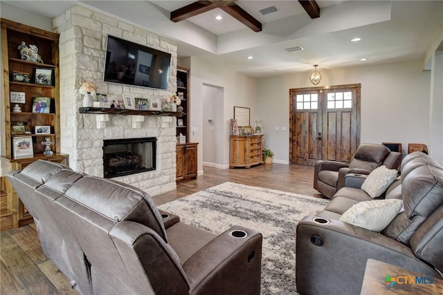 living room featuring visible vents, baseboards, beam ceiling, a fireplace, and wood finished floors