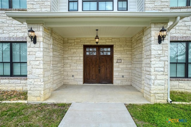 property entrance featuring stone siding, covered porch, and an attached garage