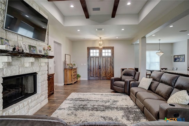 living area with dark wood-style floors, visible vents, beamed ceiling, and a wealth of natural light