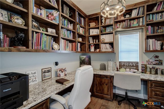 office area with built in study area, an inviting chandelier, and dark wood-style flooring