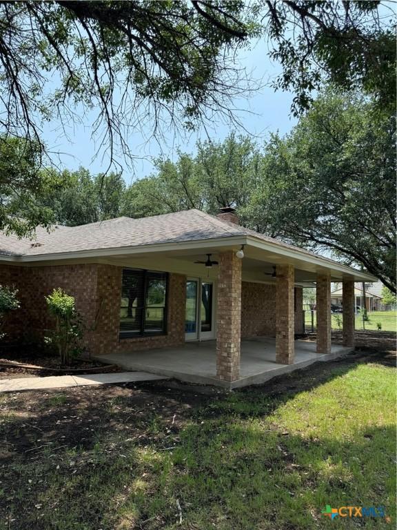 6601 Wells Fargo Rd, Killeen, TX 76542 - back of property with brick siding, a patio area, a shingled roof, and a chimney