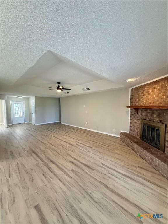 6601 Wells Fargo Rd, Killeen, TX 76542 - unfurnished living room with a textured ceiling, a brick fireplace, baseboards, a ceiling fan, and wood finished floors