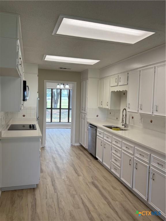 6601 Wells Fargo Rd, Killeen, TX 76542 - kitchen featuring a sink, dishwasher, black electric stovetop, light wood-style flooring, and decorative backsplash