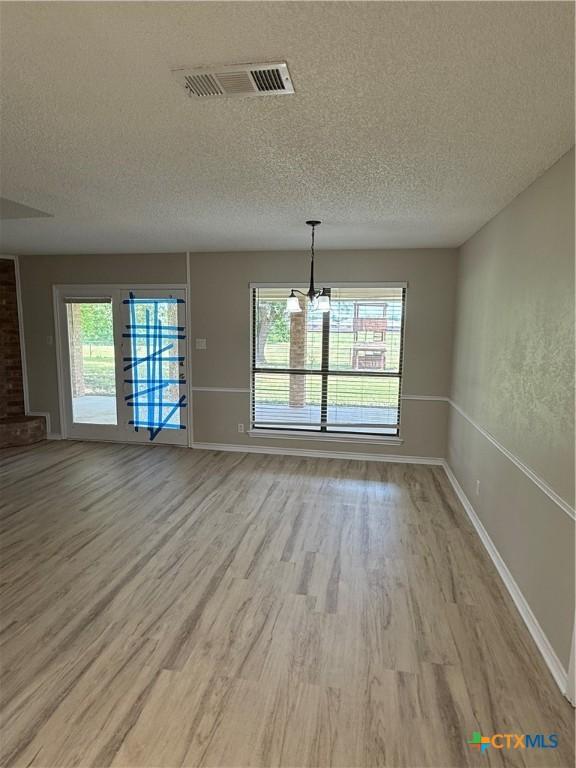 6601 Wells Fargo Rd, Killeen, TX 76542 - unfurnished dining area featuring light wood-type flooring, a textured ceiling, a chandelier, and baseboards