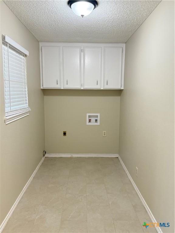 6601 Wells Fargo Rd, Killeen, TX 76542 - laundry area featuring hookup for a washing machine, cabinet space, electric dryer hookup, a textured ceiling, and baseboards