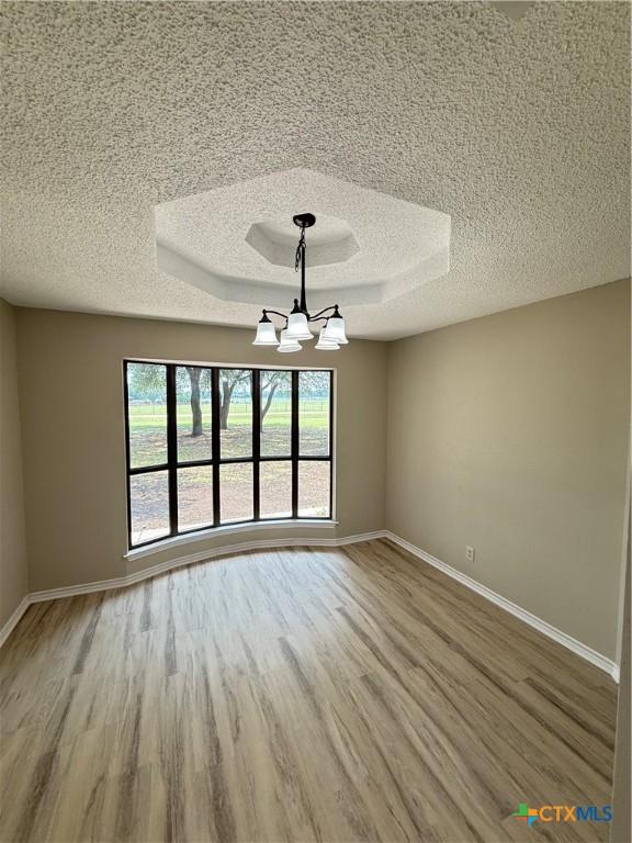 6601 Wells Fargo Rd, Killeen, TX 76542 - unfurnished room featuring wood finished floors, a textured ceiling, baseboards, and a chandelier