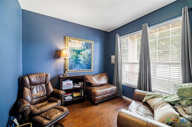 living area featuring baseboards, a textured wall, and wood finished floors