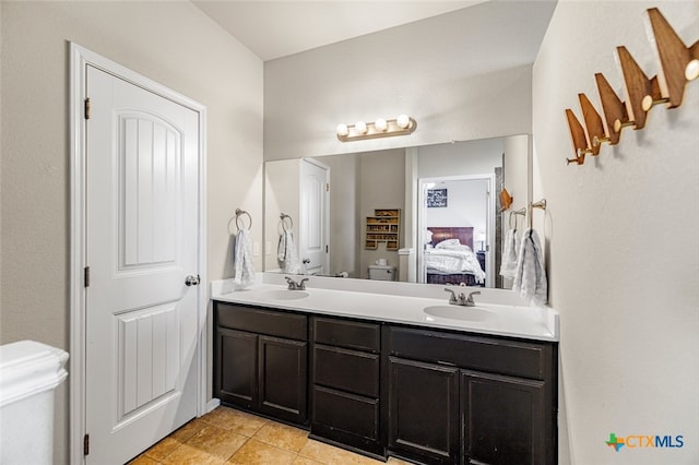 ensuite bathroom with connected bathroom, toilet, a sink, and double vanity
