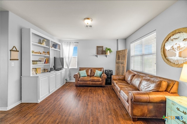 living room featuring baseboards, visible vents, and wood finished floors