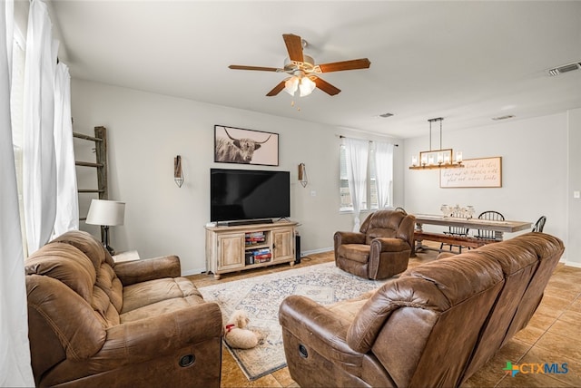 living room featuring baseboards, visible vents, light tile patterned floors, and ceiling fan with notable chandelier
