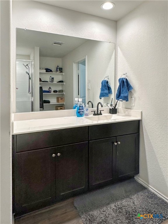 bathroom with hardwood / wood-style flooring, vanity, and walk in shower