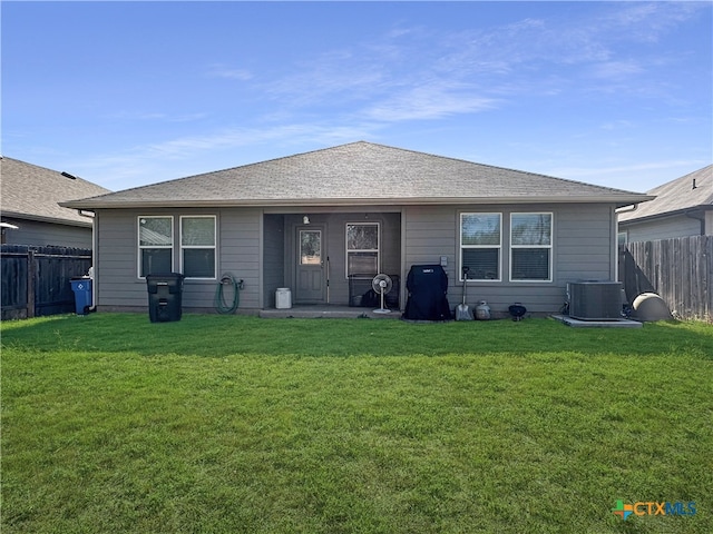 rear view of house with a yard and central AC