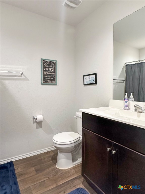 bathroom with wood-type flooring, vanity, and toilet