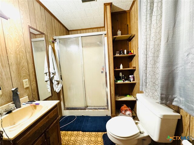 bathroom featuring vanity, wood walls, tile patterned flooring, toilet, and a shower with shower door