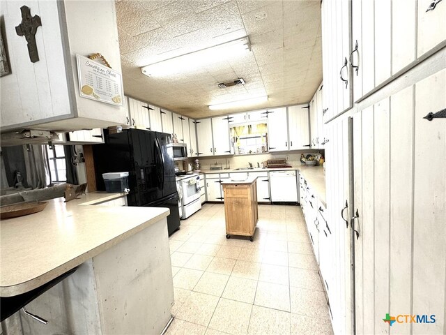 kitchen with kitchen peninsula, white appliances, sink, and white cabinets