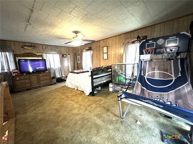 bedroom with wood walls, ceiling fan, and carpet floors