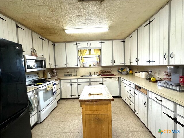 kitchen featuring white cabinetry, a center island, white appliances, and sink