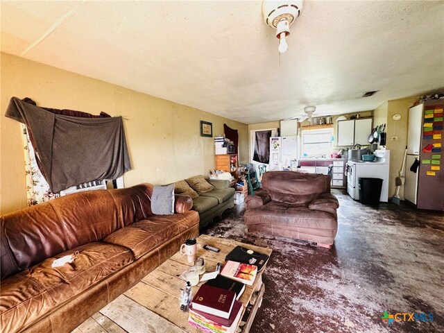 living room with a textured ceiling, concrete flooring, and ceiling fan