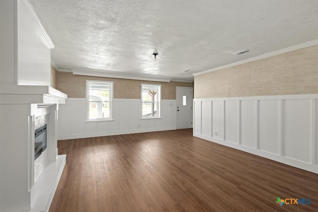 unfurnished living room with a glass covered fireplace, a textured ceiling, a wainscoted wall, and wood finished floors