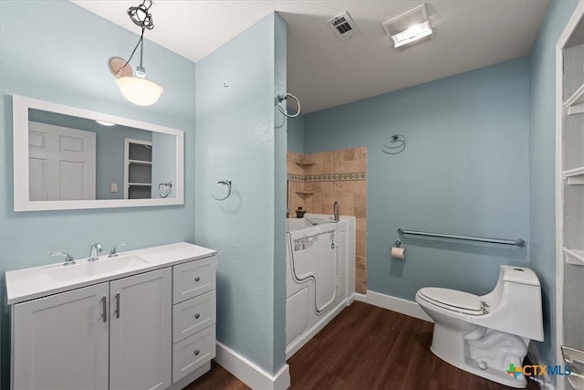 full bathroom with visible vents, toilet, wood finished floors, baseboards, and vanity