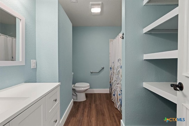 bathroom featuring vanity, toilet, wood finished floors, and baseboards