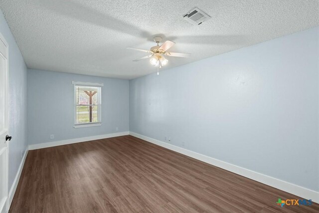 empty room featuring visible vents, baseboards, and dark wood-style flooring