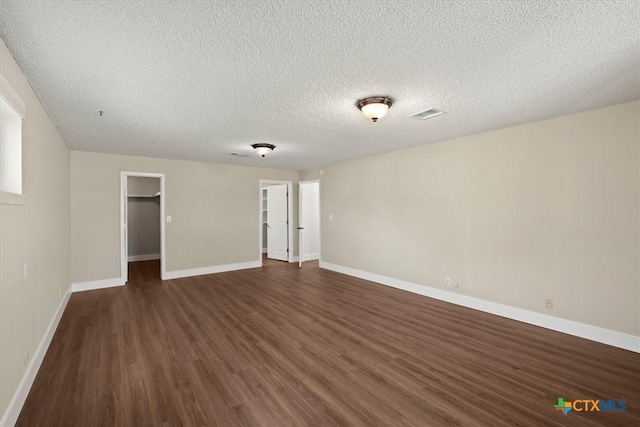 spare room featuring dark wood finished floors, visible vents, a textured ceiling, and baseboards