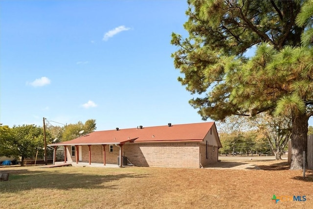 exterior space featuring brick siding, a front lawn, and a patio area