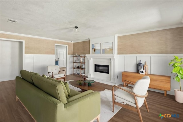 living area featuring a wainscoted wall, a glass covered fireplace, wood finished floors, and visible vents