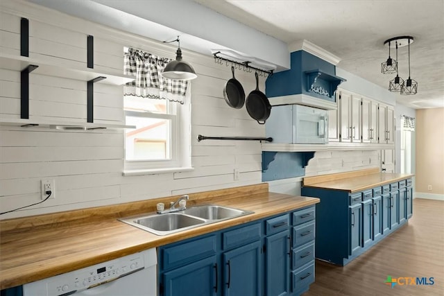 kitchen with blue cabinetry, wooden counters, dishwasher, and a sink