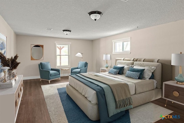 bedroom featuring radiator heating unit, wood finished floors, baseboards, and a textured ceiling