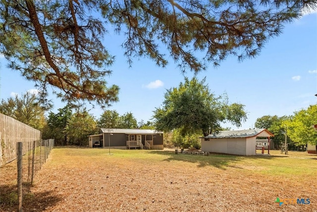 view of yard with an outbuilding, a sunroom, and fence