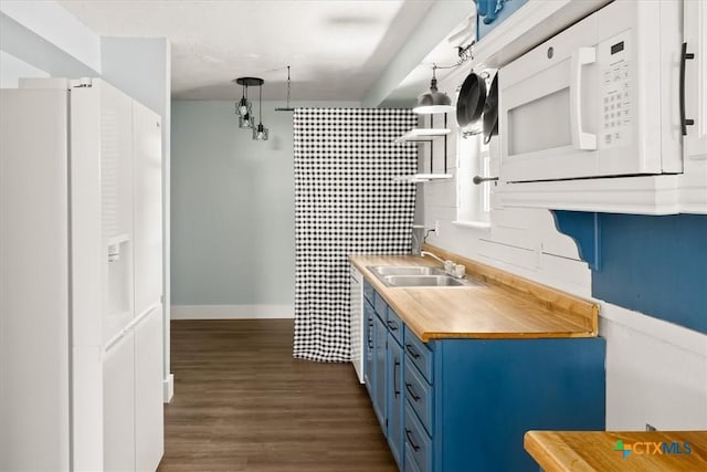 kitchen featuring a sink, blue cabinetry, butcher block counters, white appliances, and dark wood-style flooring