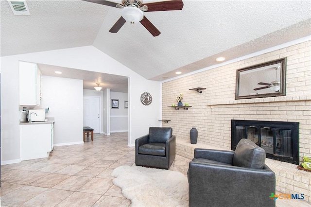 812 Trail Crest Dr, Harker Heights, TX 76548 - living room featuring ceiling fan, a brick fireplace, a textured ceiling, vaulted ceiling, and visible vents