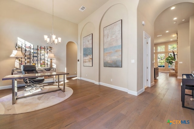 office with an inviting chandelier, a high ceiling, and hardwood / wood-style floors