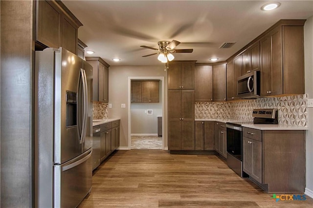 kitchen with appliances with stainless steel finishes, wood finished floors, visible vents, and tasteful backsplash