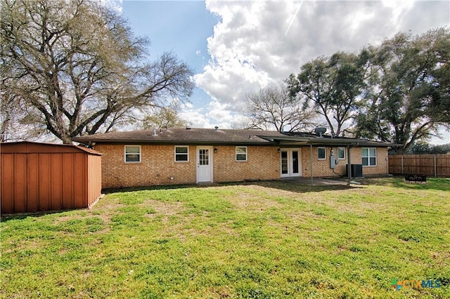 back of house featuring an outbuilding, a yard, fence, french doors, and a shed