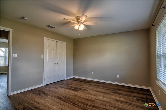 unfurnished bedroom with baseboards, visible vents, and dark wood finished floors