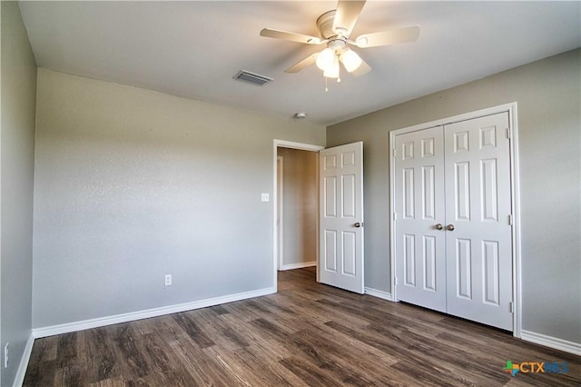 unfurnished bedroom with dark wood-style floors, a closet, visible vents, and baseboards