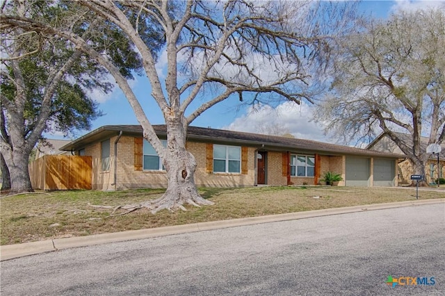 single story home featuring driveway, an attached garage, fence, a front lawn, and brick siding