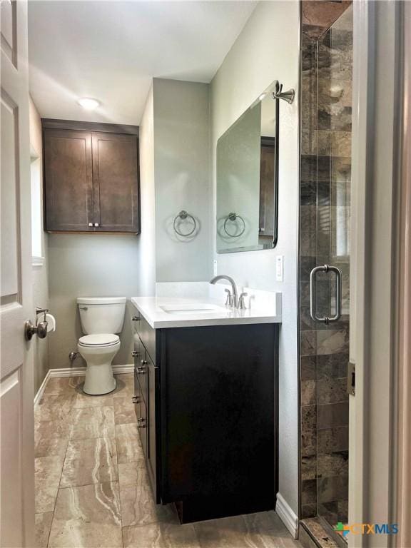 bathroom featuring toilet, vanity, baseboards, marble finish floor, and a shower stall